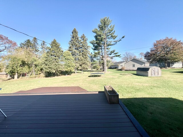 wooden deck with a lawn and a storage shed