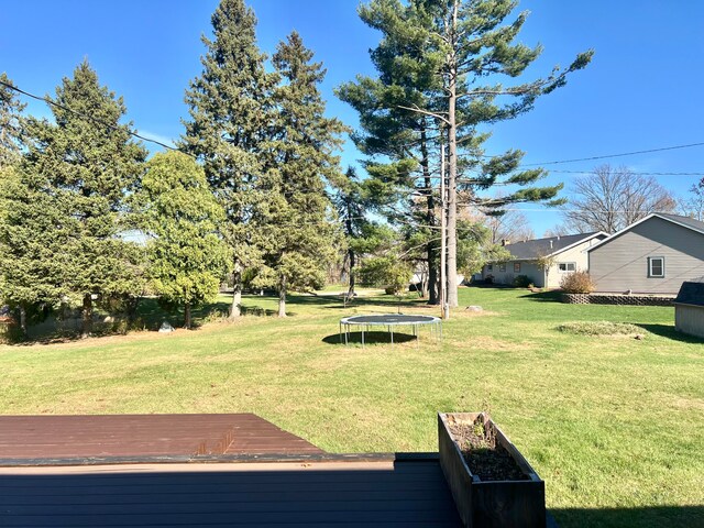 view of yard with a trampoline and a wooden deck