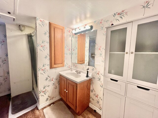 bathroom featuring hardwood / wood-style floors, vanity, and a shower