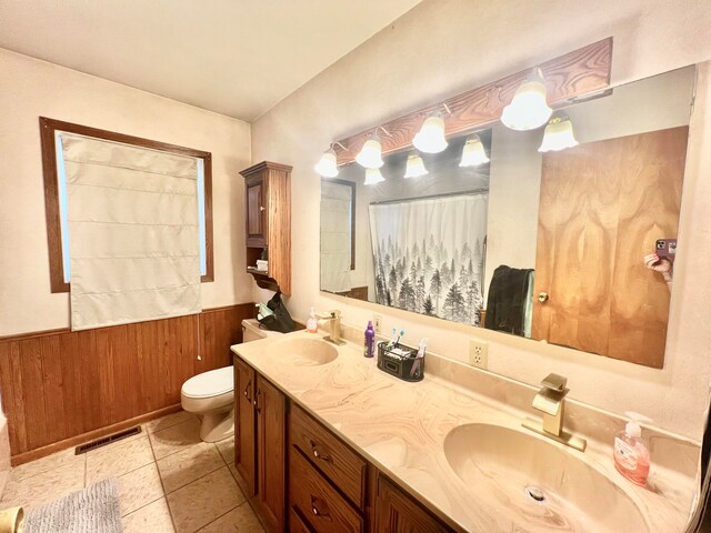 bathroom featuring wooden walls, tile patterned flooring, vanity, and toilet