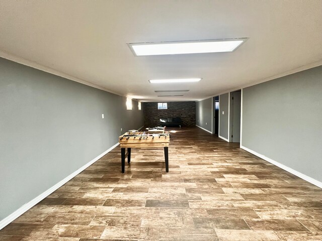 rec room with wood-type flooring, a brick fireplace, and crown molding