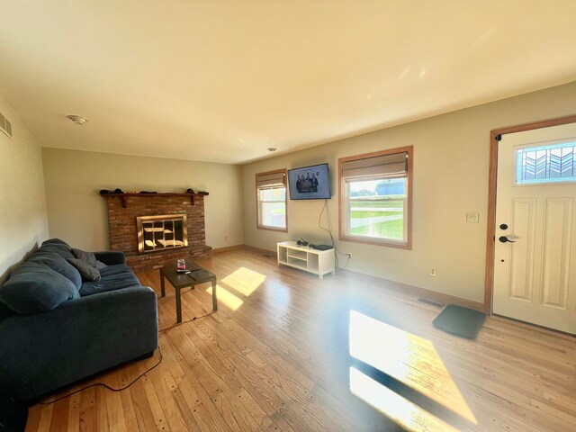 living room featuring a brick fireplace and light wood-type flooring