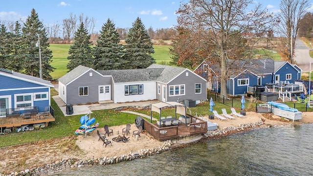 back of house with central AC unit, an outdoor fire pit, and a deck with water view