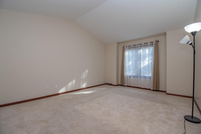 carpeted spare room featuring vaulted ceiling