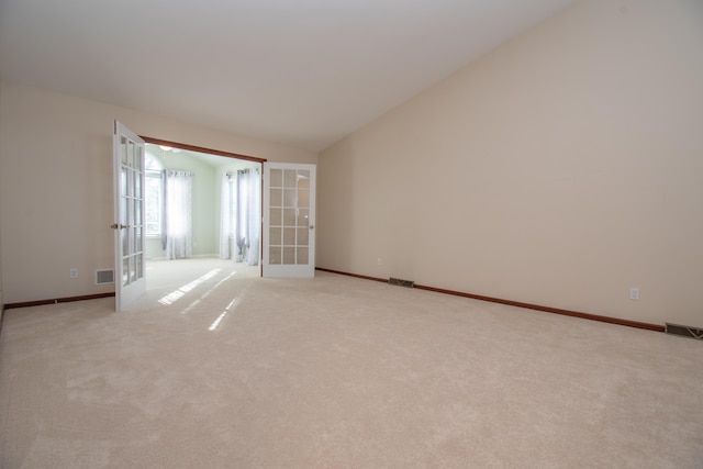 unfurnished room with french doors, vaulted ceiling, and light carpet