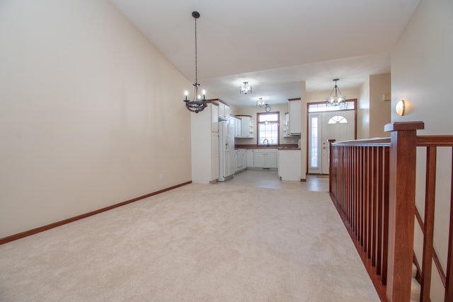 interior space with lofted ceiling, sink, light colored carpet, and an inviting chandelier