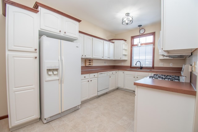 kitchen with hanging light fixtures, sink, white cabinets, and white appliances