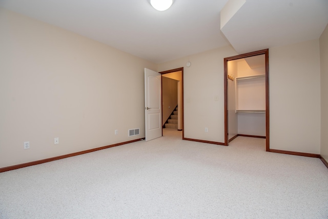 unfurnished bedroom featuring a walk in closet, light carpet, and a closet