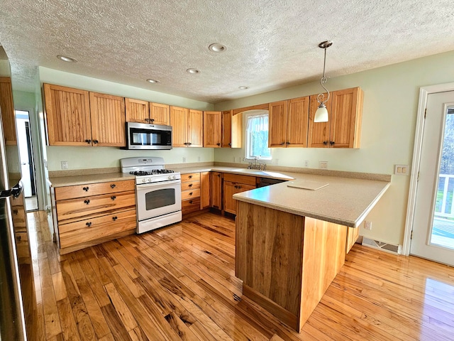 kitchen featuring light wood-type flooring, decorative light fixtures, white gas range, a textured ceiling, and kitchen peninsula