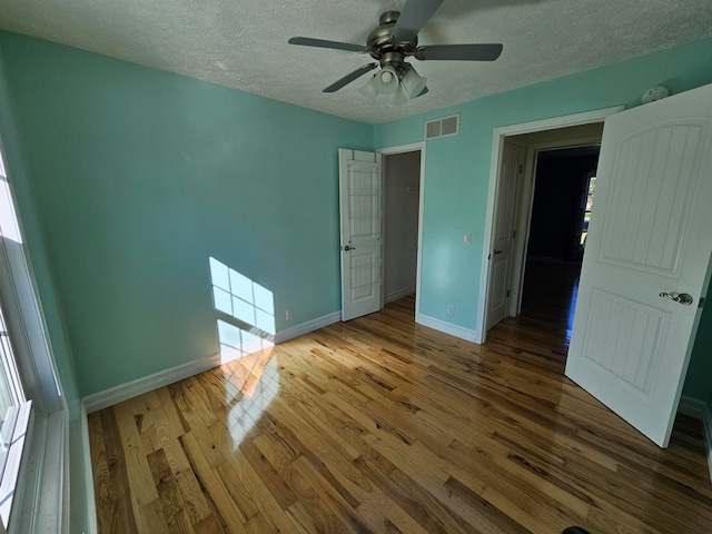 unfurnished bedroom with a textured ceiling, wood-type flooring, and ceiling fan