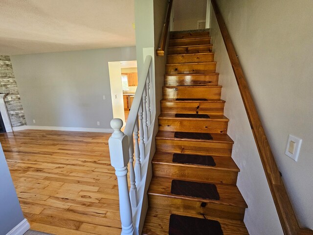 stairway with hardwood / wood-style floors and a fireplace