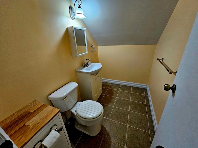 bathroom with tile patterned flooring, lofted ceiling, toilet, and vanity