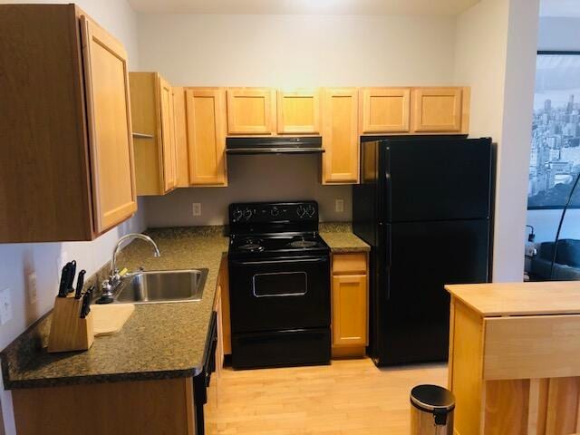 kitchen featuring sink, black appliances, dark stone counters, light brown cabinets, and light wood-type flooring