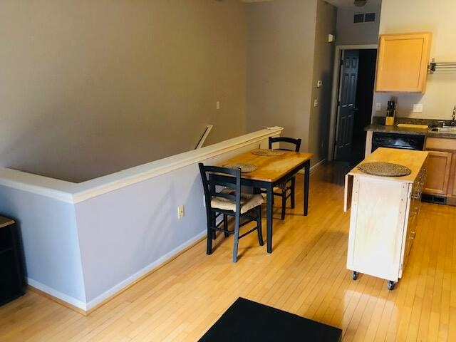 kitchen featuring light hardwood / wood-style floors, a center island, black dishwasher, sink, and light brown cabinets