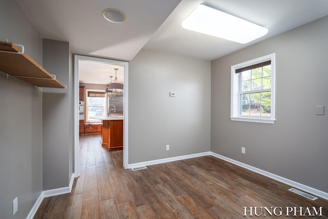 empty room with dark hardwood / wood-style floors and an inviting chandelier