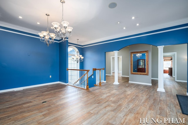 empty room with ornamental molding, wood-type flooring, and decorative columns