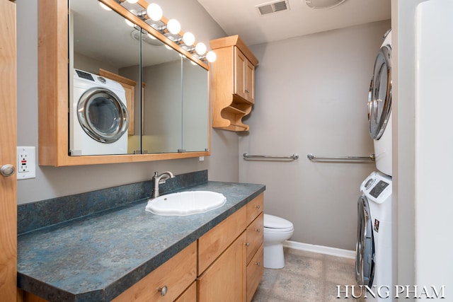 bathroom featuring stacked washer / dryer, vanity, and toilet