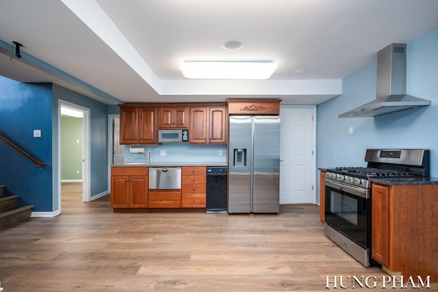 kitchen with appliances with stainless steel finishes, wall chimney exhaust hood, light hardwood / wood-style floors, and sink