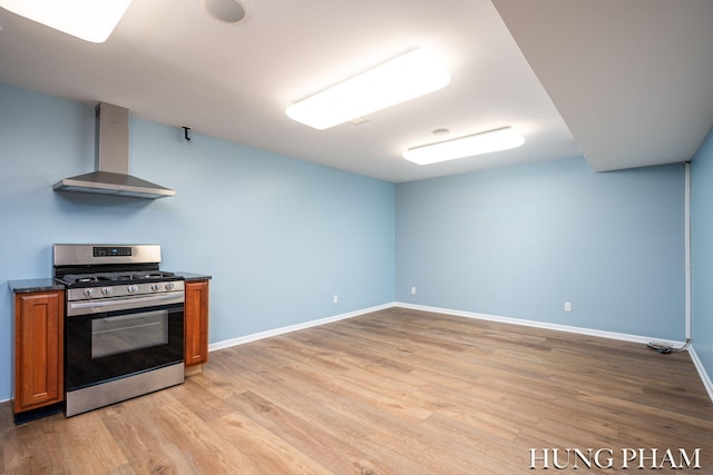 kitchen featuring light wood-type flooring, stainless steel gas stove, and wall chimney range hood