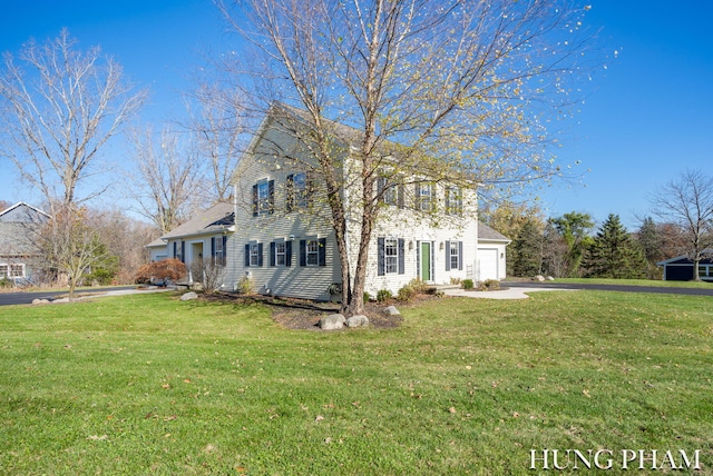 colonial inspired home with a garage and a front yard