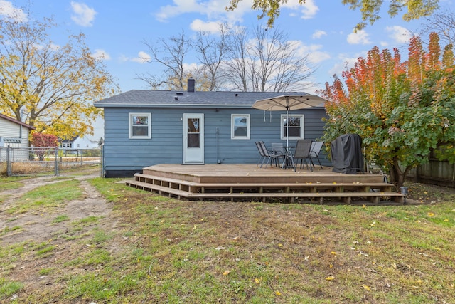 back of house featuring a gate, fence, a yard, a wooden deck, and a chimney