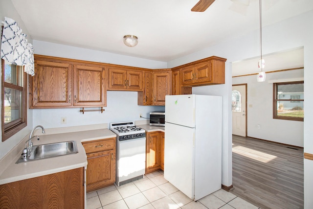 kitchen with white appliances, sink, pendant lighting, and light hardwood / wood-style floors