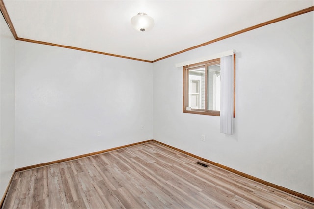 spare room featuring light wood-type flooring and crown molding