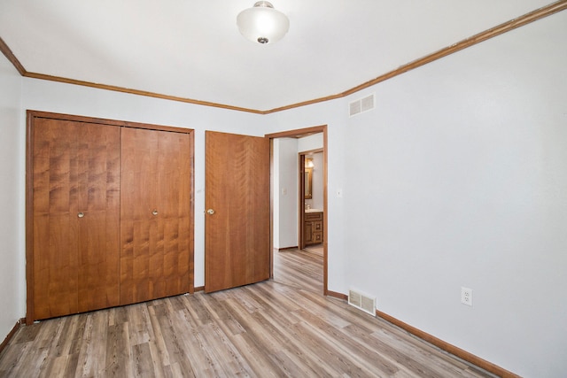 unfurnished bedroom featuring light hardwood / wood-style floors, crown molding, and a closet