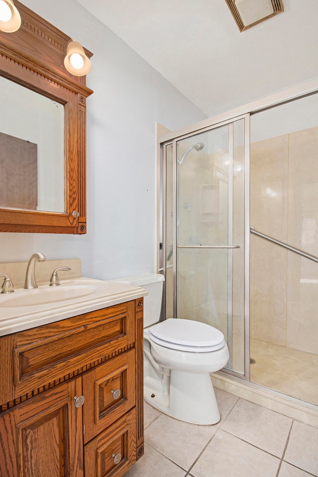 bathroom featuring toilet, vanity, tile patterned flooring, and a shower with shower door