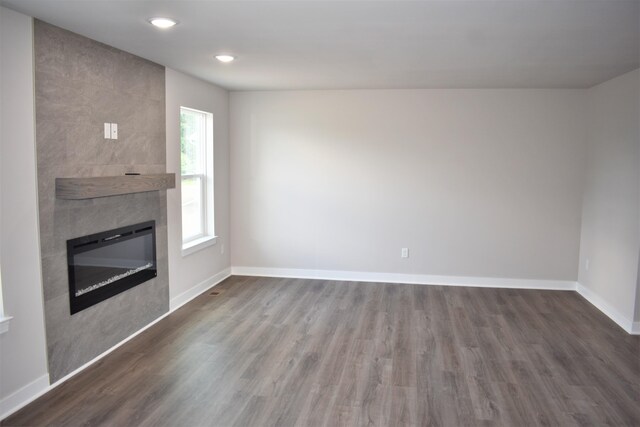 unfurnished living room with dark hardwood / wood-style flooring and a tiled fireplace