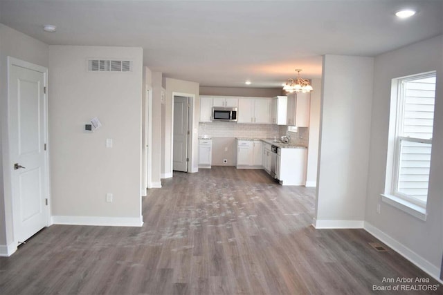 kitchen featuring stainless steel appliances, dark wood-type flooring, white cabinets, and decorative backsplash