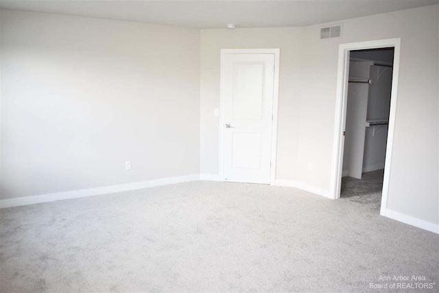 unfurnished bedroom with a walk in closet, carpet floors, and a closet