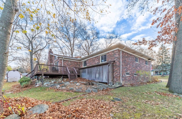 rear view of property featuring a lawn, a shed, and a deck