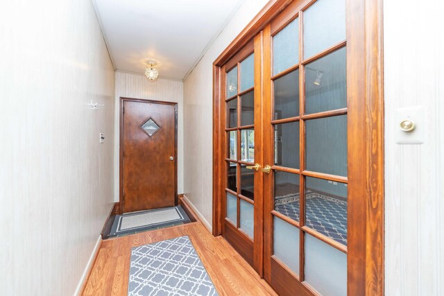 doorway to outside featuring wood-type flooring and crown molding