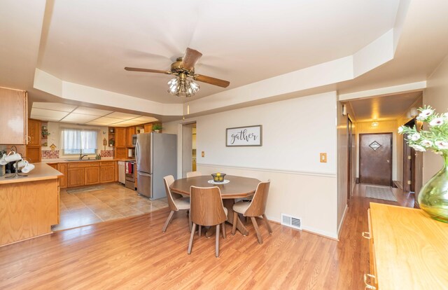 dining room with light wood-type flooring, ceiling fan, and sink