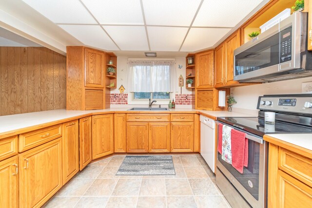 kitchen with sink, appliances with stainless steel finishes, a drop ceiling, light tile patterned floors, and backsplash