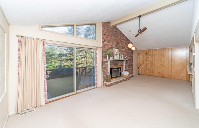 unfurnished living room with carpet flooring, a fireplace, wood walls, and lofted ceiling with beams