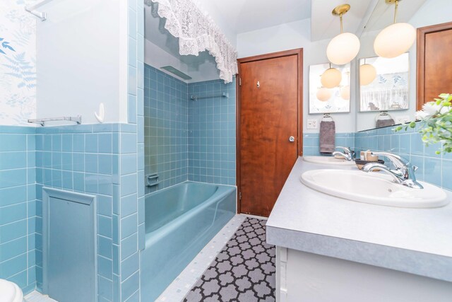 bathroom with vanity, tiled shower / bath combo, and tile walls