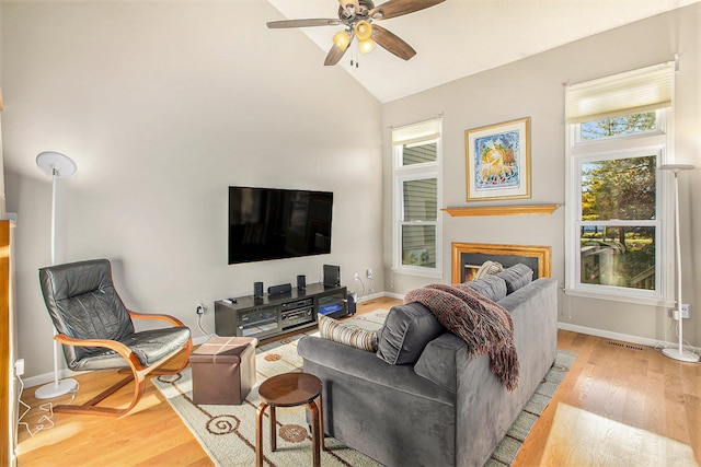 living room with light hardwood / wood-style floors, ceiling fan, and high vaulted ceiling