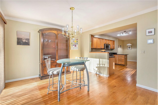 dining area with ornamental molding, a chandelier, and light hardwood / wood-style floors