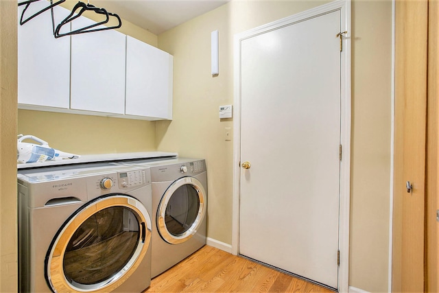 washroom with cabinets, light hardwood / wood-style flooring, and washer and clothes dryer