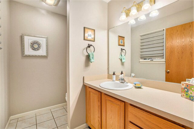 bathroom with toilet, vanity, and tile patterned floors