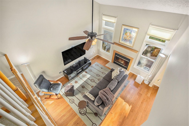 living room featuring light hardwood / wood-style floors, ceiling fan, a textured ceiling, and high vaulted ceiling