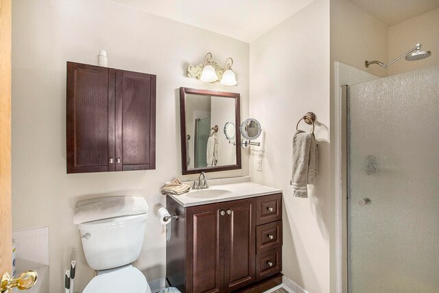 bathroom with toilet, vanity, and a shower with door