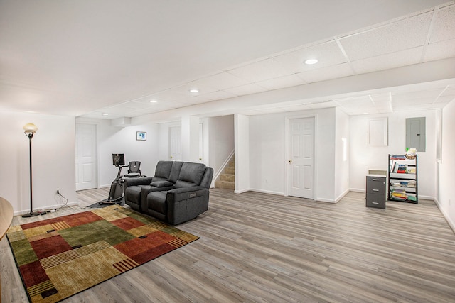 living room featuring electric panel, light hardwood / wood-style flooring, and a drop ceiling