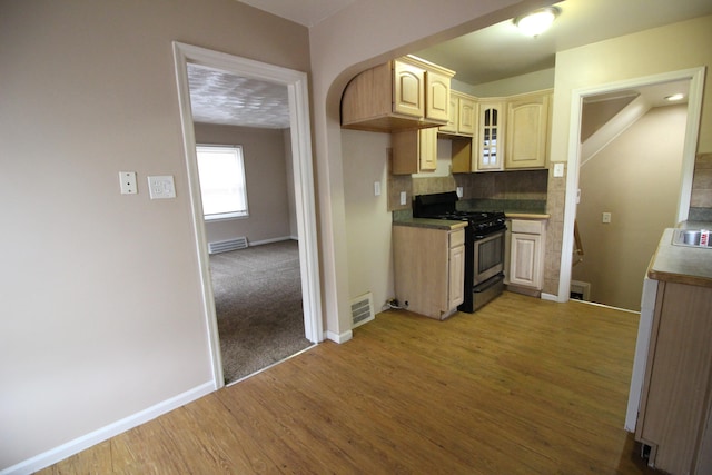 kitchen with light brown cabinets, decorative backsplash, wood-type flooring, and black gas range oven