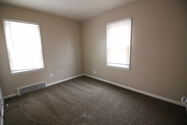 unfurnished room featuring a healthy amount of sunlight and dark carpet