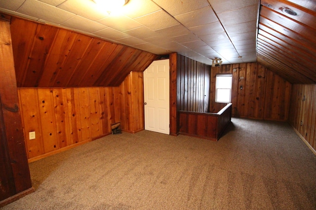 bonus room with wood walls, lofted ceiling, and carpet floors