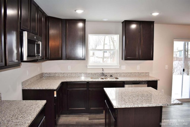 kitchen featuring sink, stainless steel appliances, dark hardwood / wood-style floors, dark brown cabinetry, and light stone counters