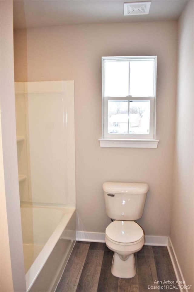 bathroom with hardwood / wood-style flooring, a bathing tub, and toilet